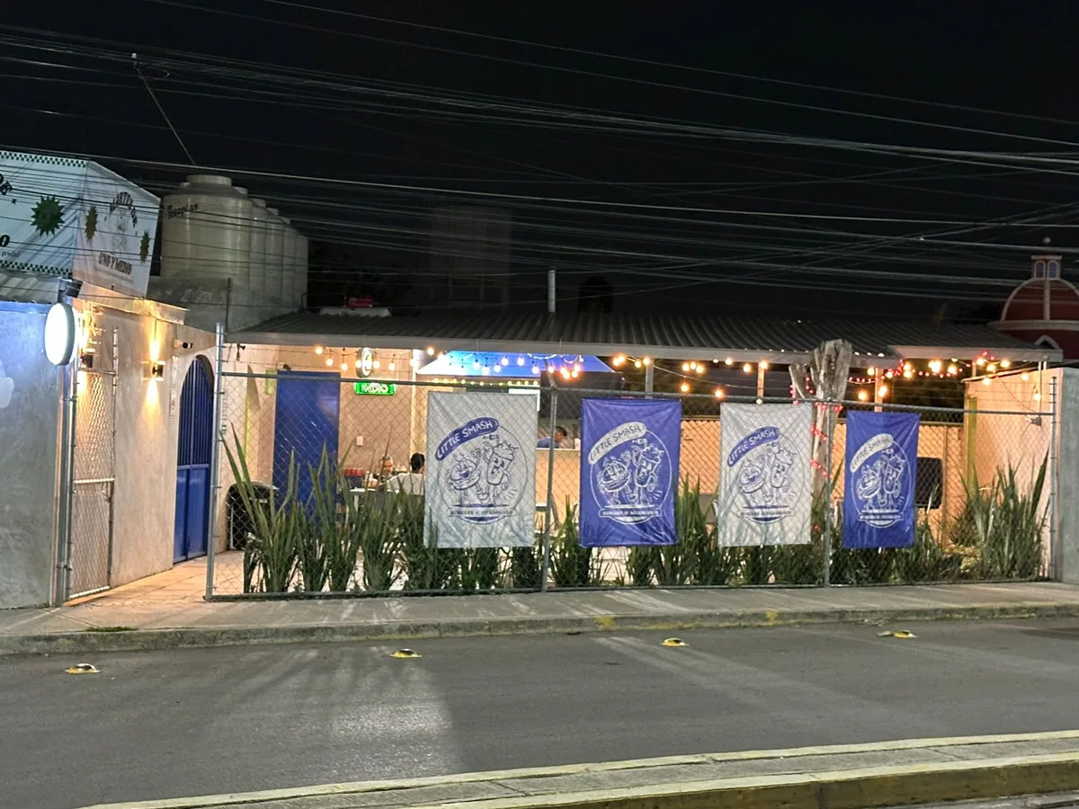 Fachada de Little Smash de noche, con luces
